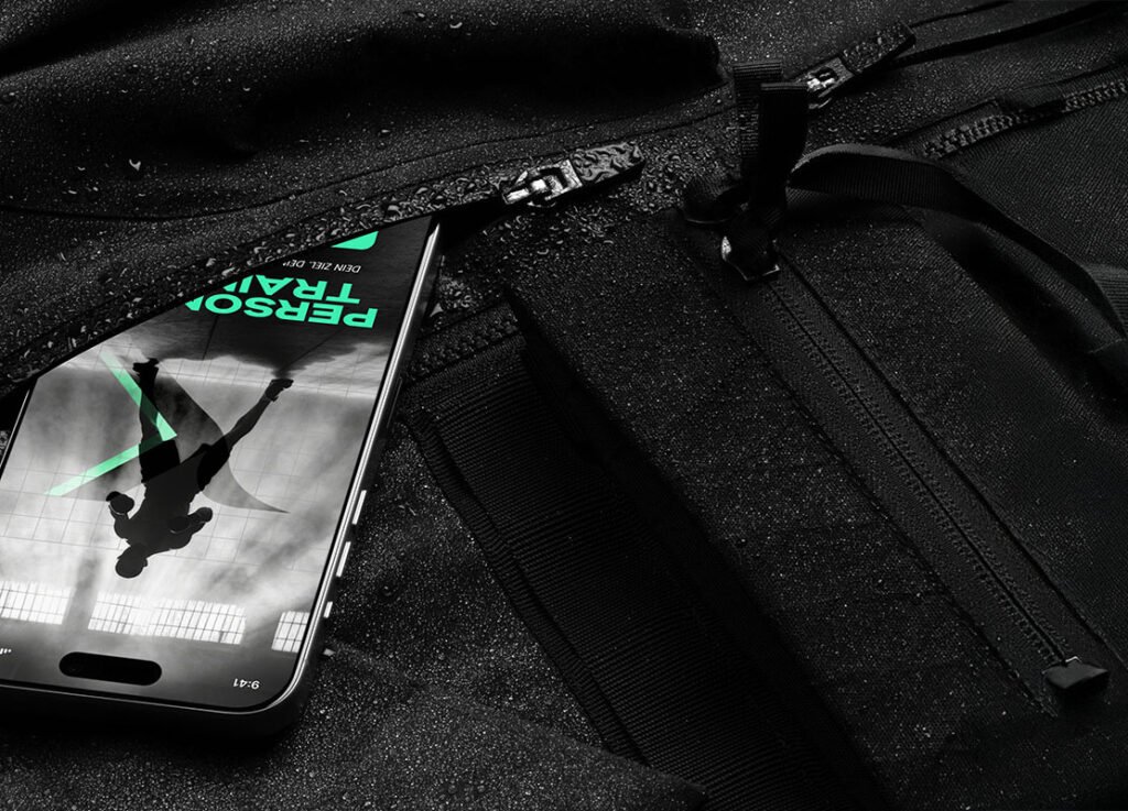Smartphone mit geöffneter Fitness-App „Personal Training“ liegt in schwarzer Sporttasche – sportlicher Look mit Lichtreflexen