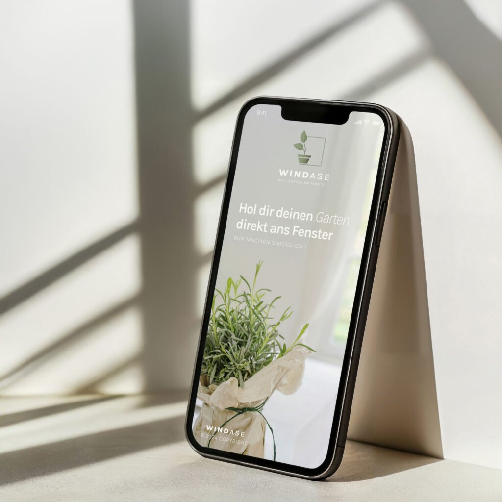 Smartphone mit geöffneter Windase-App steht vor heller Wand – natürliches Licht- und Schattenspiel im Interior-Setting