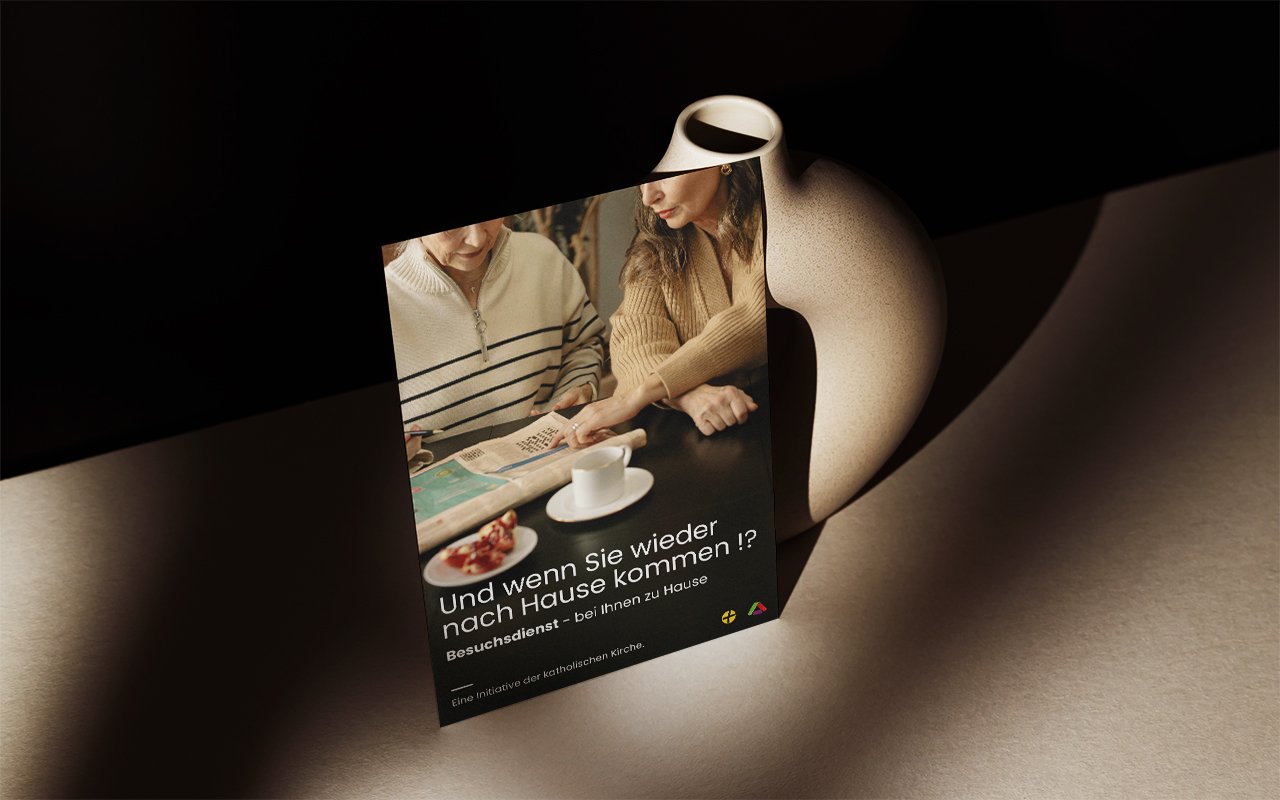 Plakat auf Tisch gelehnt, zeigt emotionales Bildmotiv und Text zur Nachsorge-Initiative "Und wenn Sie wieder nach Hause kommen!?"