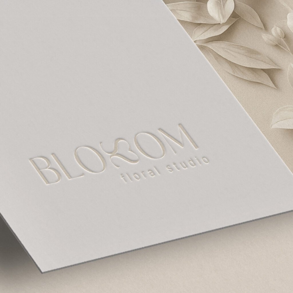 Geprägtes Blossom-Logo auf cremefarbener Karte mit floralen Elementen