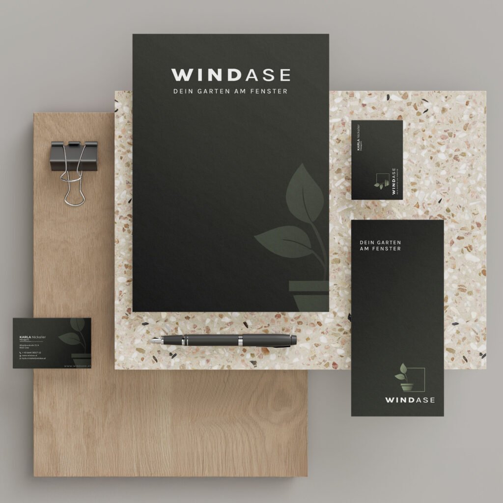apierprodukte, Visitenkarte & Notizheft mit Windase-Logo flach arrangiert – naturverbundene Geschäftsausstattung in dunklem Branding-Design
