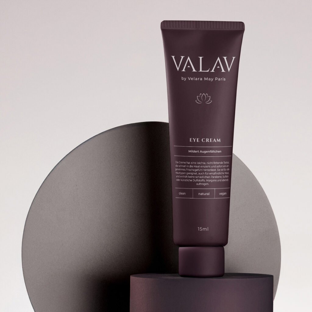VALAV Eye Cream in burgunderfarbener Tube, stehend auf geometrischen Formen vor beigem Hintergrund – minimalistisches Produktfoto