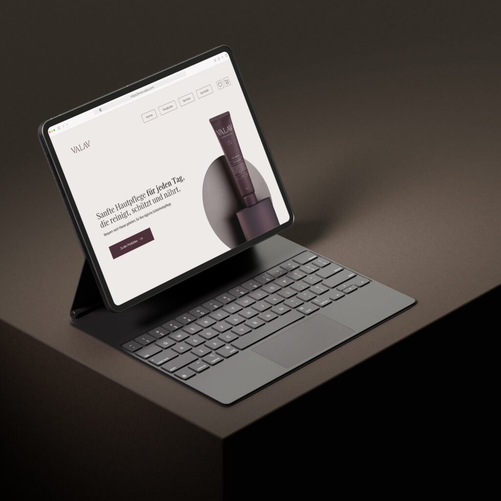 Tablet mit VALAV-Website auf einem braunen Würfel, zeigt Produktseite mit Handcreme im eleganten Design