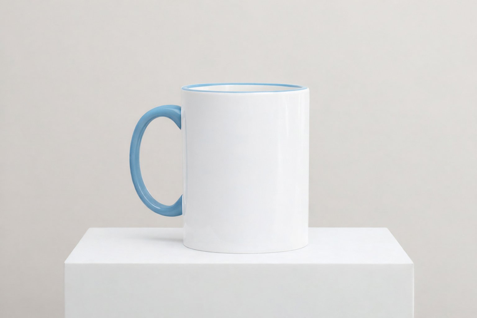 Weiße Keramiktasse mit hellblauen Henkel und hellblauen Innenrand auf weißem Podest vor neutralem Hintergrund
