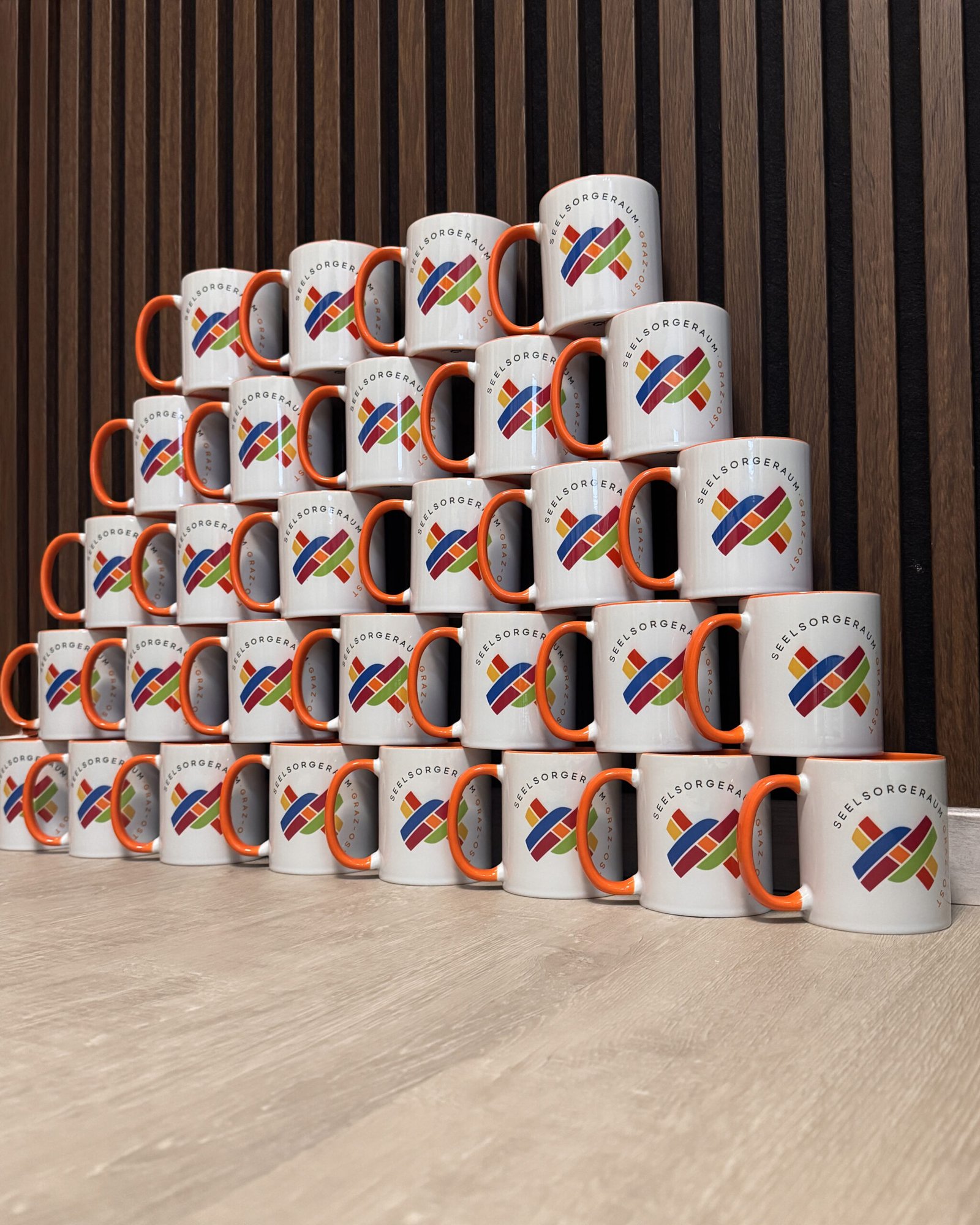 Gestapelte personalisierte Kaffeetassen mit Logo des Seelsorgeraums Graz Ost als Werbemittel