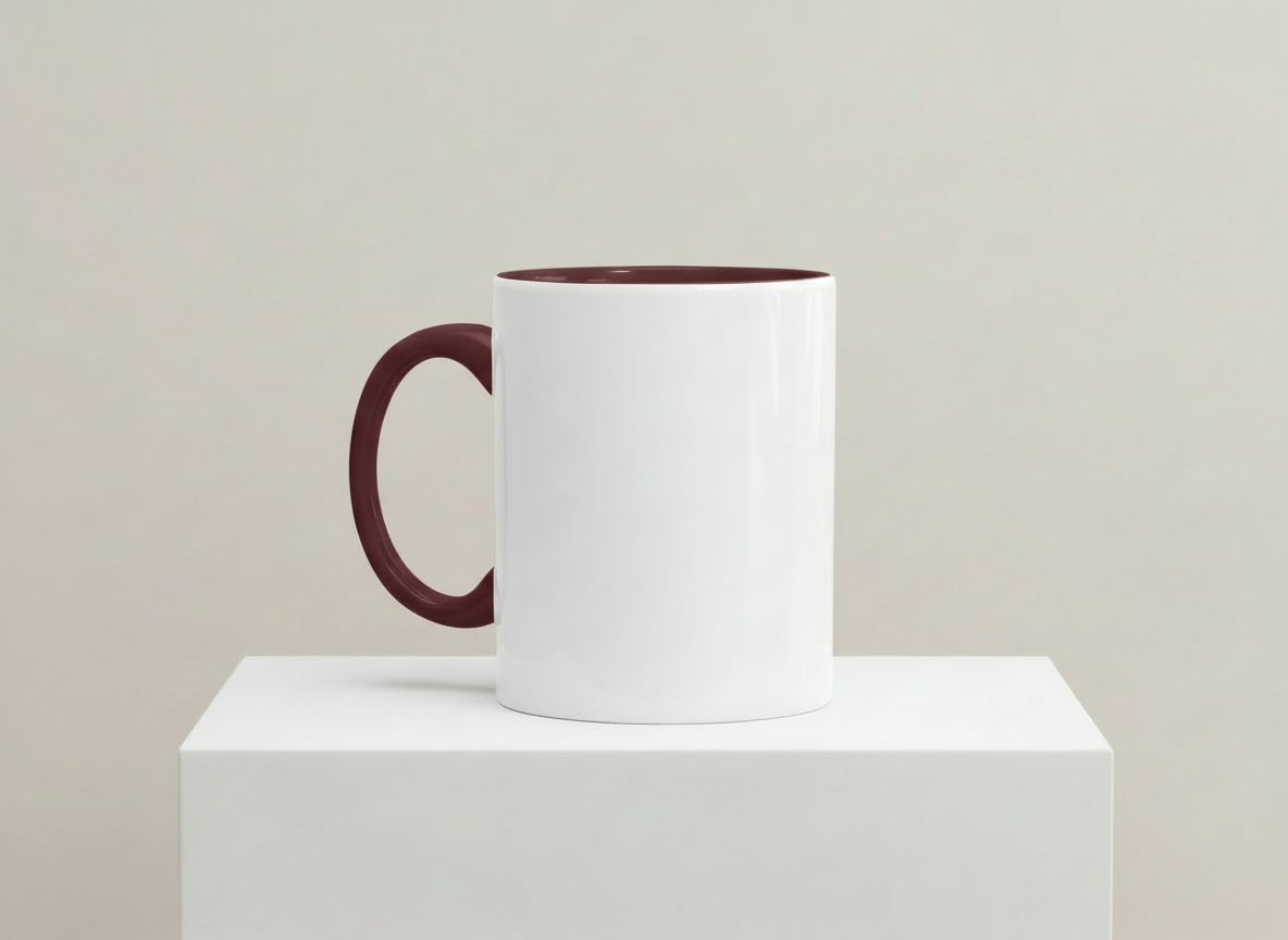 Weiße Keramiktasse mit weinrotem Henkel und weinrotem Innenrand auf weißem Podest vor neutralem Hintergrund