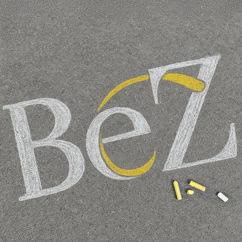 BeZ-Logo als Kreidezeichnung auf Betonboden mit weißen und gelben Kreidestücken.