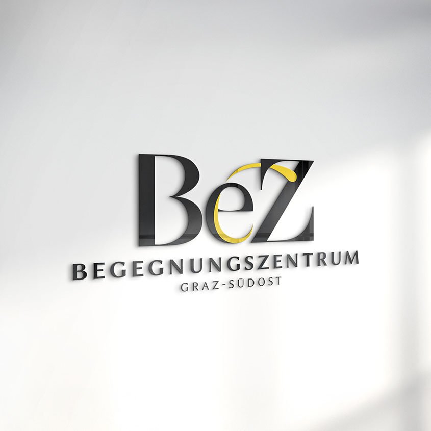 Logo des Begegnungszentrums Graz-Südost mit schwarzer und gelber Schrift auf heller Wand