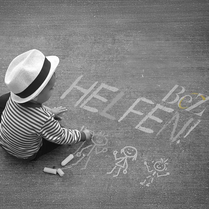 Kind zeichnet mit Kreide auf Betonboden, Schriftzug „HEL FEN!“ mit BeZ-Logo, Symbol für Hilfe und Gemeinschaft.