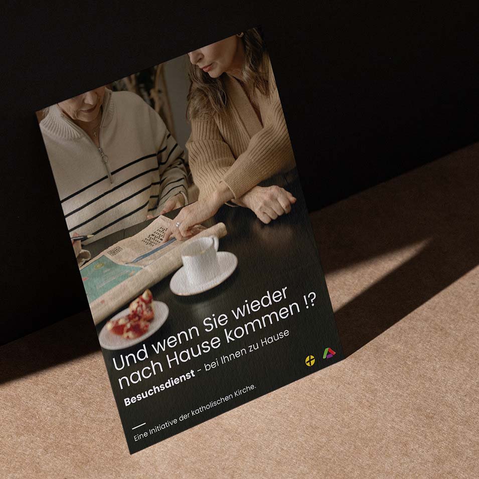 Plakat auf Tisch gelehnt, zeigt emotionales Bildmotiv und Text zur Nachsorge-Initiative "Und wenn Sie wieder nach Hause kommen!?"