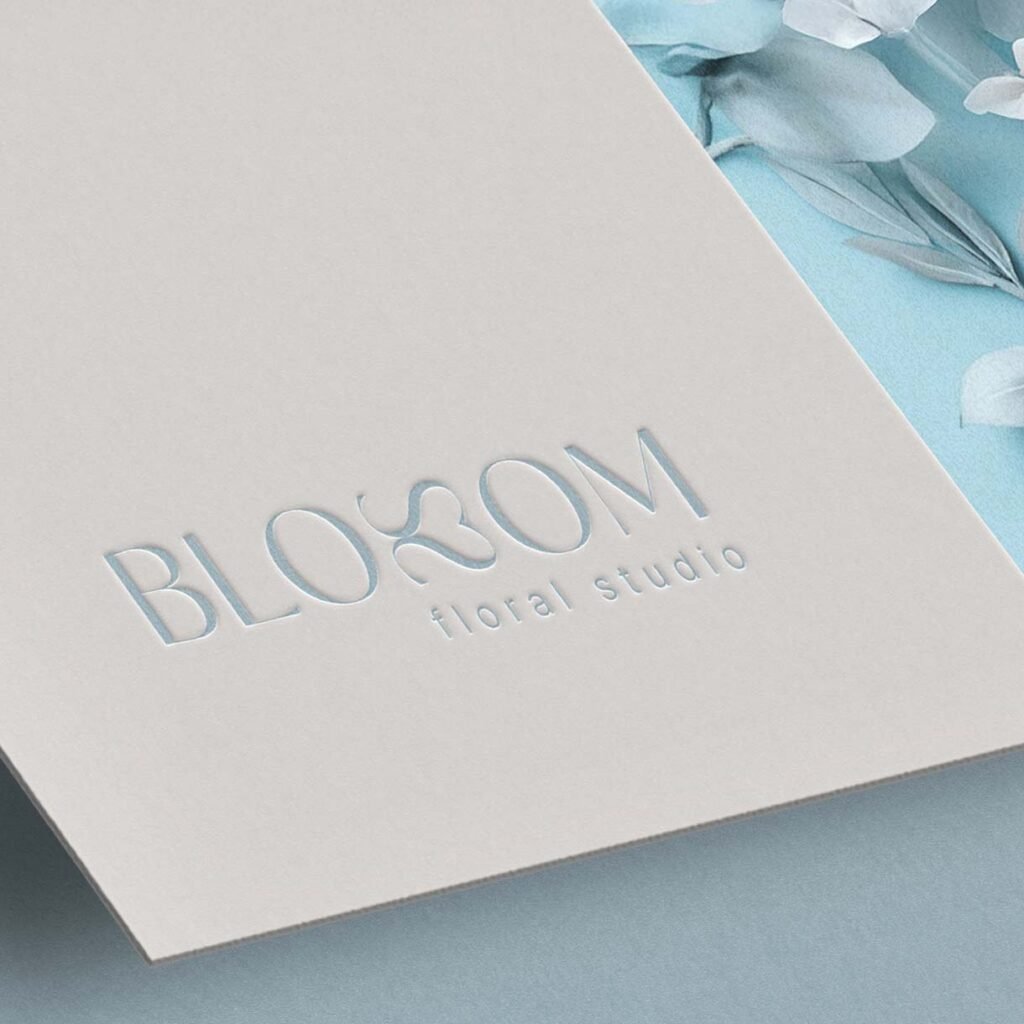 Geprägtes Blossom-Logo auf cremefarbener Karte mit blauen Blütenblättern