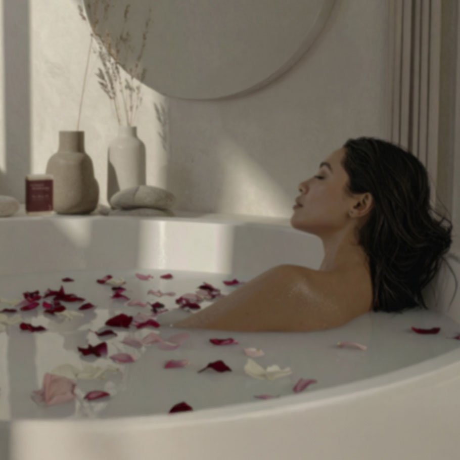 Frau entspannt in einer Badewanne mit Rosenblättern, minimalistisches Interior in Naturtönen.
