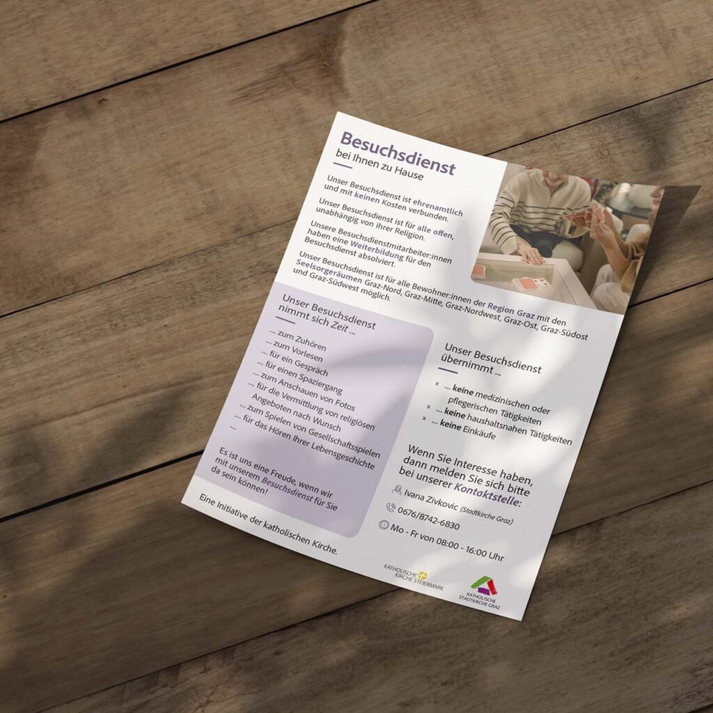Rückseite eines Flyers zum Besuchsdienst auf Holztisch – mit Kontaktinformationen, Ablauf und emotionalem Bildausschnitt